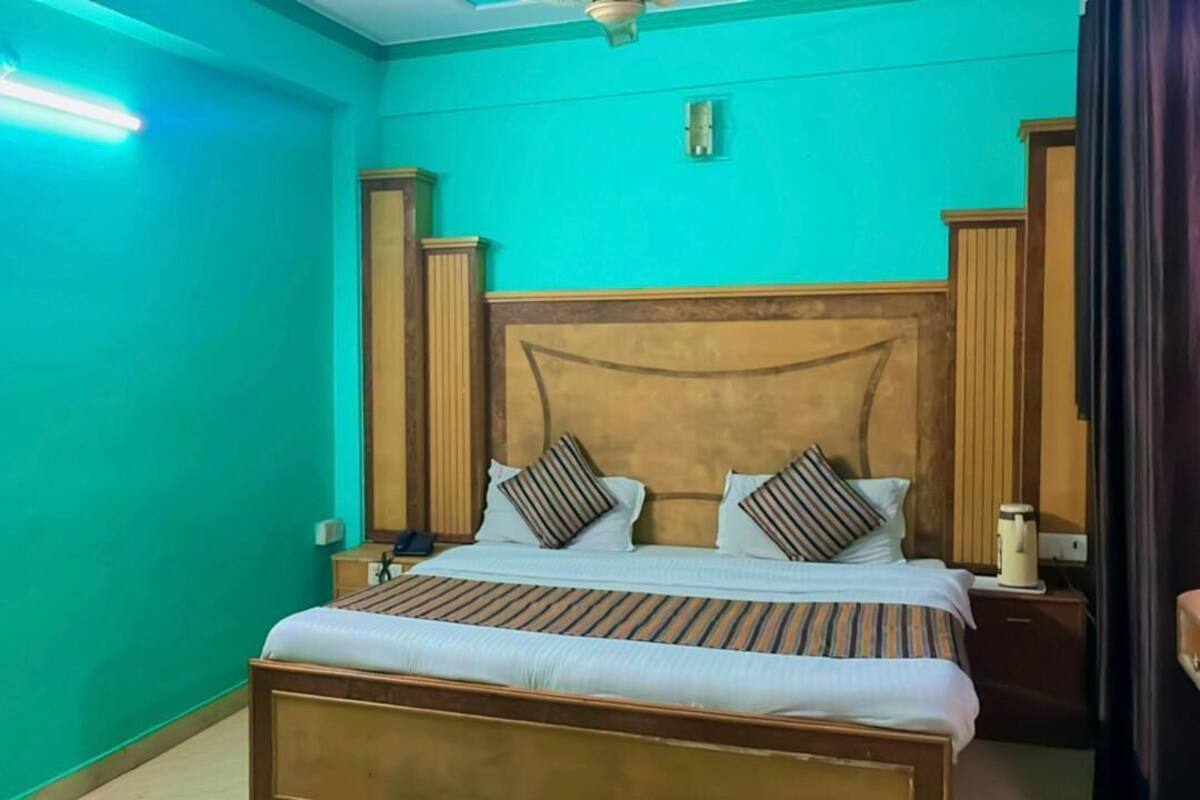A bedroom with a bed, nightstands, a ceiling fan, and teal walls.