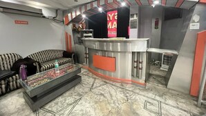 Un vestíbulo de hotel con mostrador de recepción, sofás, una mesa de centro y suelo de mármol.