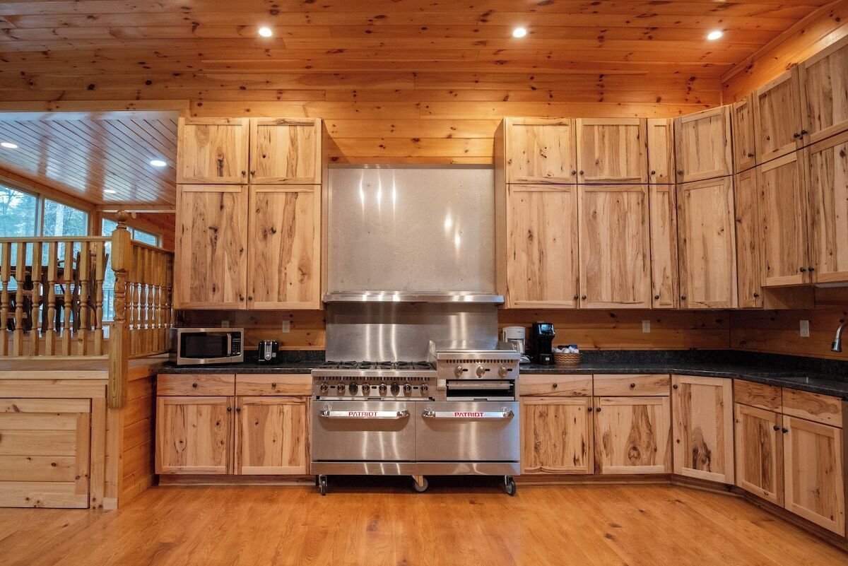 Una cucina con mobili in legno, un forno a gas in acciaio inossidabile e un forno a microonde.