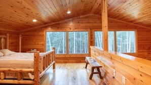 Uma cabana de madeira com quarto no mezanino, janelas amplas e um banco.