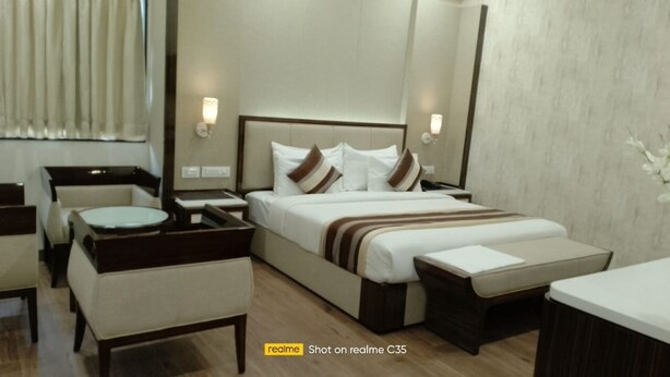 Una habitación de hotel con una cama, mesitas de noche, una silla y una pequeña mesa redonda.