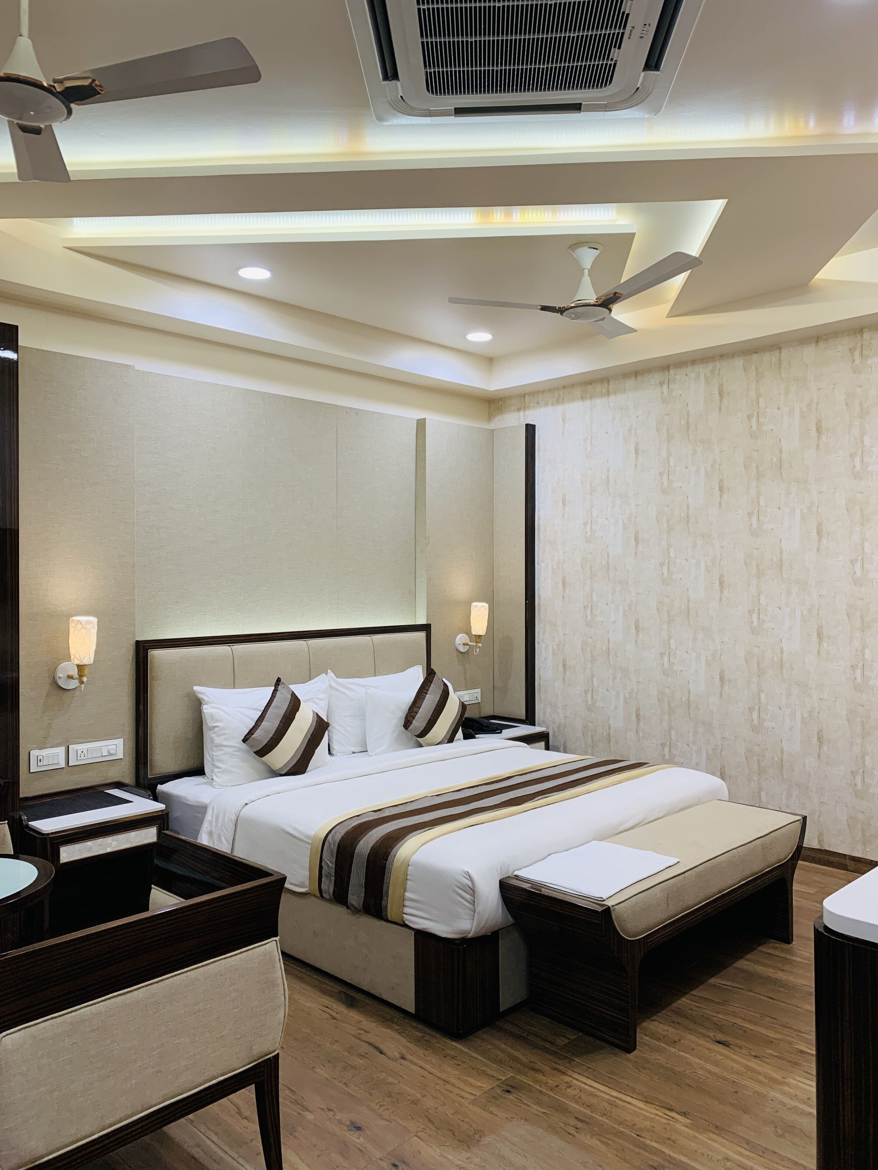 A modern hotel room with a large bed, bedside tables, a desk, and a ceiling fan.