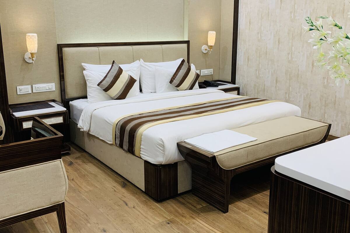 A hotel room with a large bed, bedside tables, a desk, and a chair.