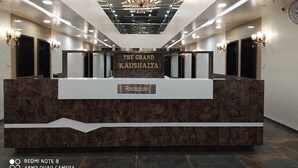 A reception area with a marble counter, chandeliers, and a sign reading "THE GRAND KAUSHALYA". - Hotel The Grand Kaushalya (Sohagpur)