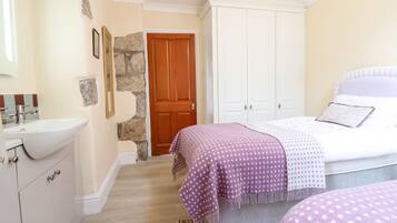 Une chambre à coucher comprenant un lit, une table de chevet, une commode et une salle de bain avec un lavabo et un miroir.