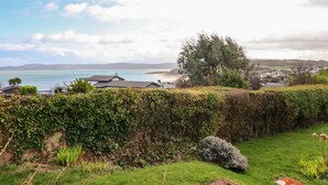 Eine Küstenlandschaft mit Blick auf das Meer, einer Hecke und einem kleinen Busch.