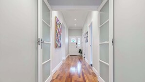 A hallway with wooden flooring, white walls, and a door at the end.