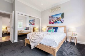 Un dormitorio con cama, mesitas de noche, un espejo y un cuadro en la pared.