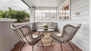 A covered patio with wicker chairs, a glass table, and a potted plant.