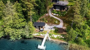 A lakeside property with a dock, two modern cabins, and a clear view of the surrounding forest.