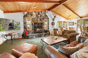 L’intérieur chaleureux d’un chalet avec une cheminée en pierre, des meubles en cuir et une griffe d’ours accrochée au mur.