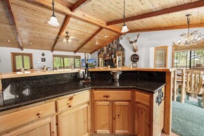 Een keuken met houten kasten, granieten werkbladen en een stenen openhaard.