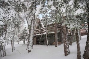 A snow-covered lodge with a wooden deck and a stone facade.