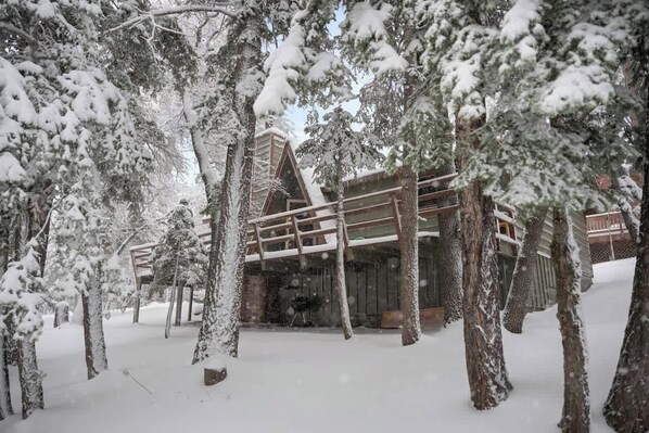 A snow-covered lodge with a wooden deck and a stone facade.
