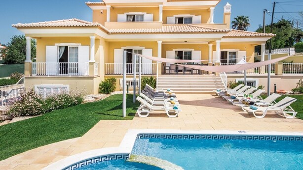 Una casa de dos pisos con piscina, mobiliario exterior y un jardín bien cuidado.