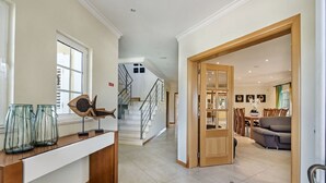 Amplia sala de estar con escalera, comedor y cocina con encimera de madera y tarros de vidrio.