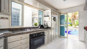 Een moderne keuken met witte kasten, een gasfornuis, een inbouwoven en een groot raam.