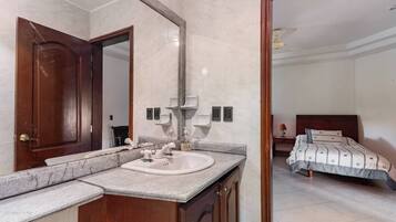 A bathroom with a marble sink, wooden cabinets, and a large mirror.