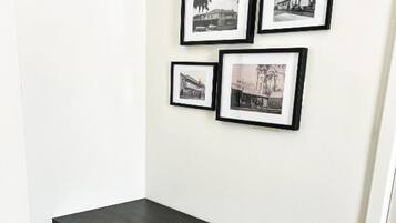 A corner room with a black desk, a grey chair, and three framed pictures on the wall.