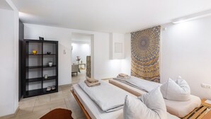 Una habitación de hotel moderna con una cama, una pequeña zona de estar, una estantería y un papel tapiz estampado.