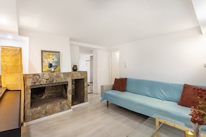 Ein Wohnzimmer mit Kamin aus Stein, einem hellblauen Sofa und einem Glastisch.