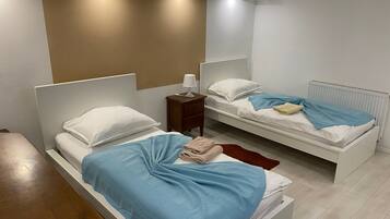 Quarto com duas camas, uma mesa de cabeceira, um abajur e um radiador.