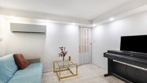 Una sala de estar moderna con un sofá, una mesa de centro de vidrio, un televisor y una puerta.