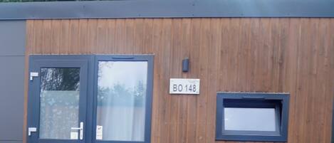 A modern building with a wooden facade, a door, a window, and a table with a cover.