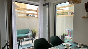 Comedor con una mesa dispuesta para cuatro, sillas y vistas a una terraza de madera.