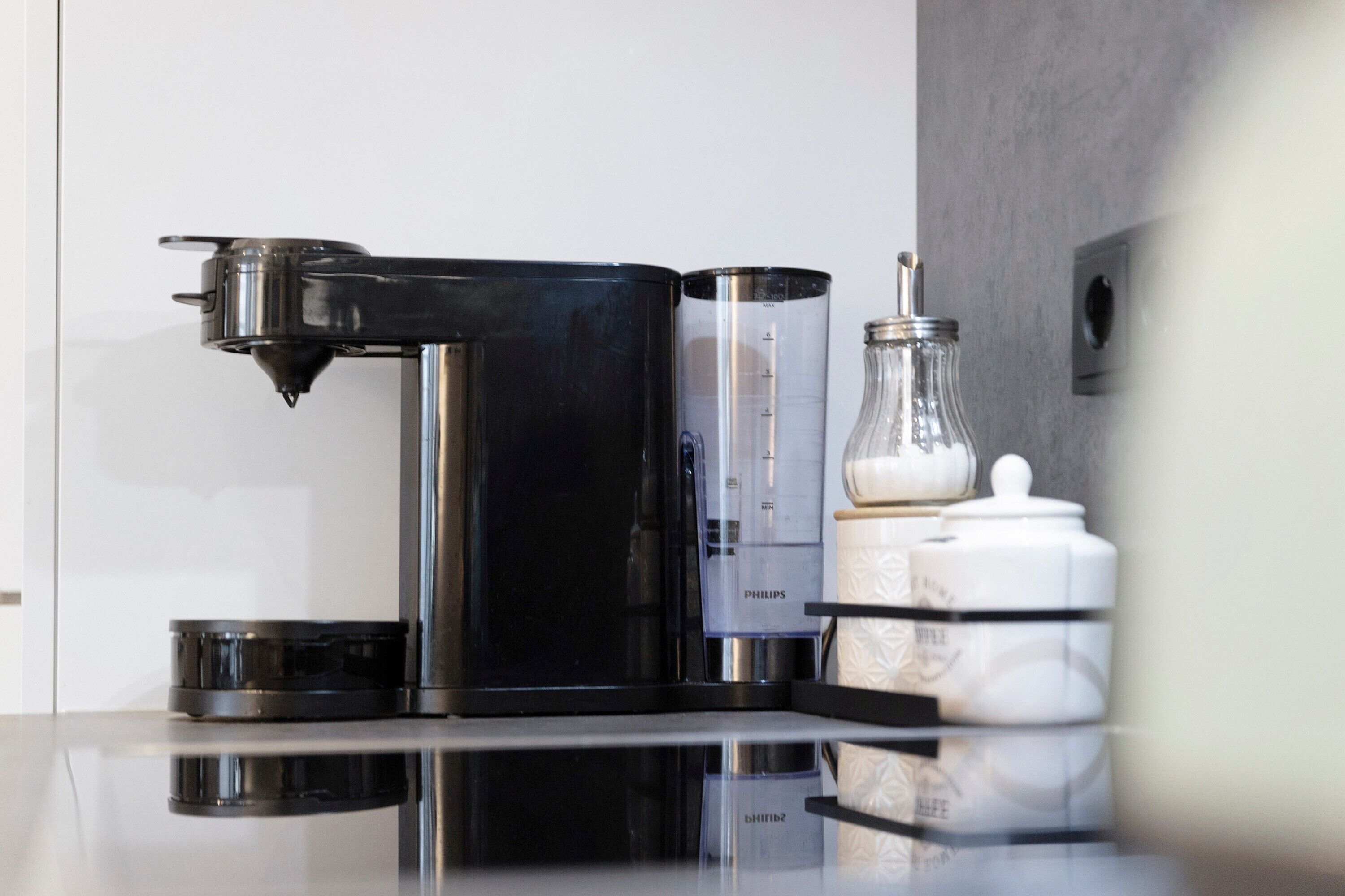 A modern kitchen with a coffee machine, a scale, and storage jars.