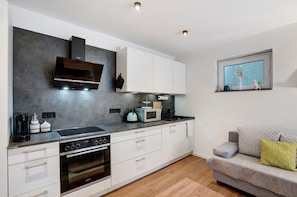 A modern kitchen with white cabinetry, a built-in oven, and a microwave.