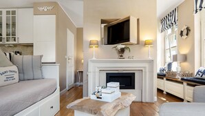 Una sala de estar acogedora con sofá, chimenea, televisor y comedor con mesa y sillas.