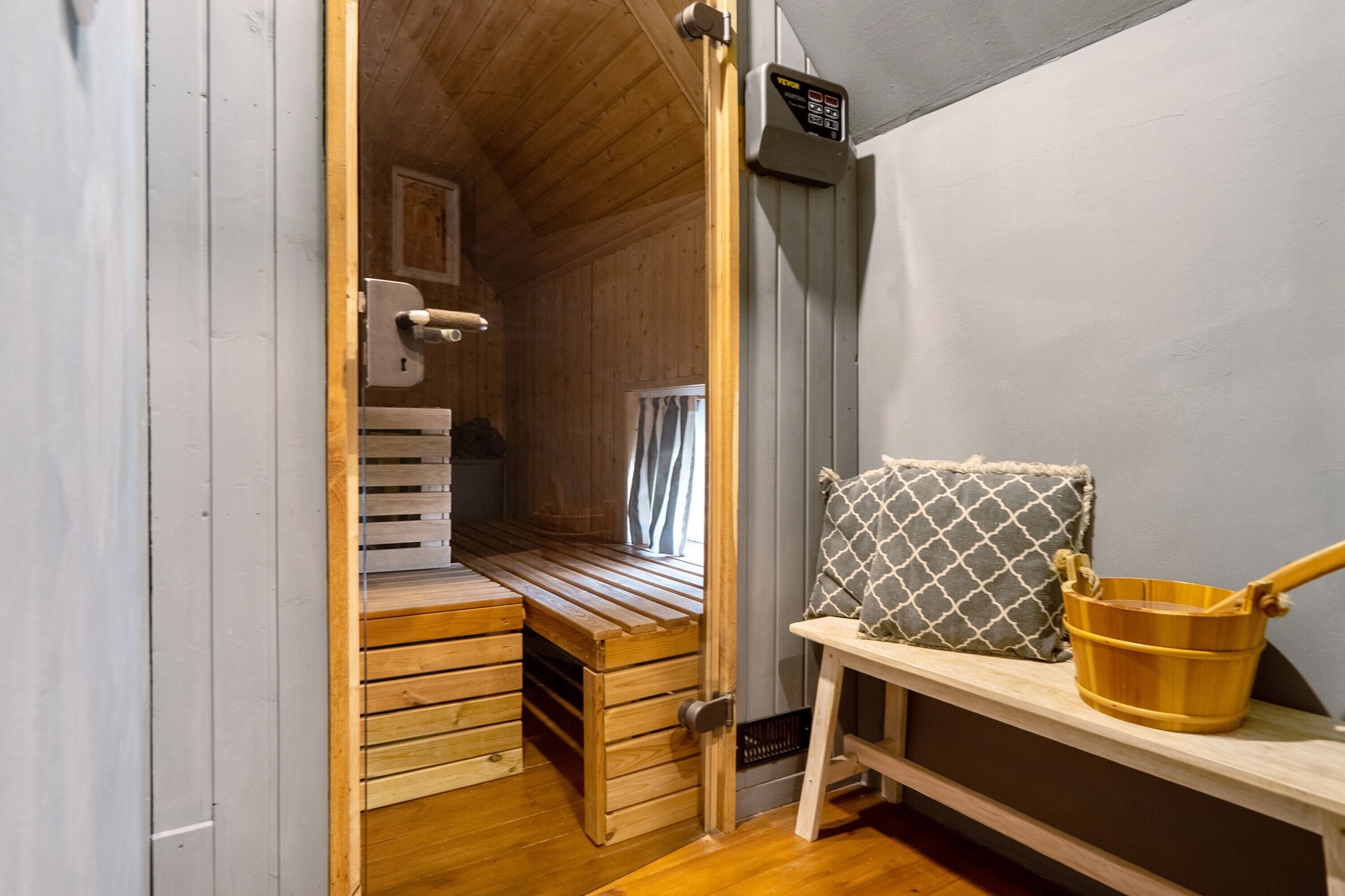 Un interior de madera con un banco, un cojín y un cubo.