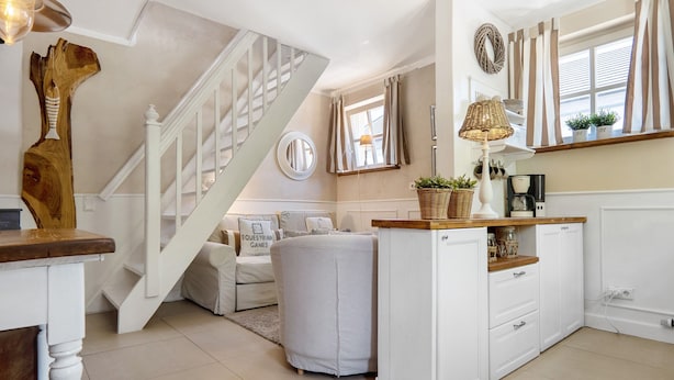 Una cocina moderna con escalera, armarios blancos y un rincón comedor con sofá blanco.