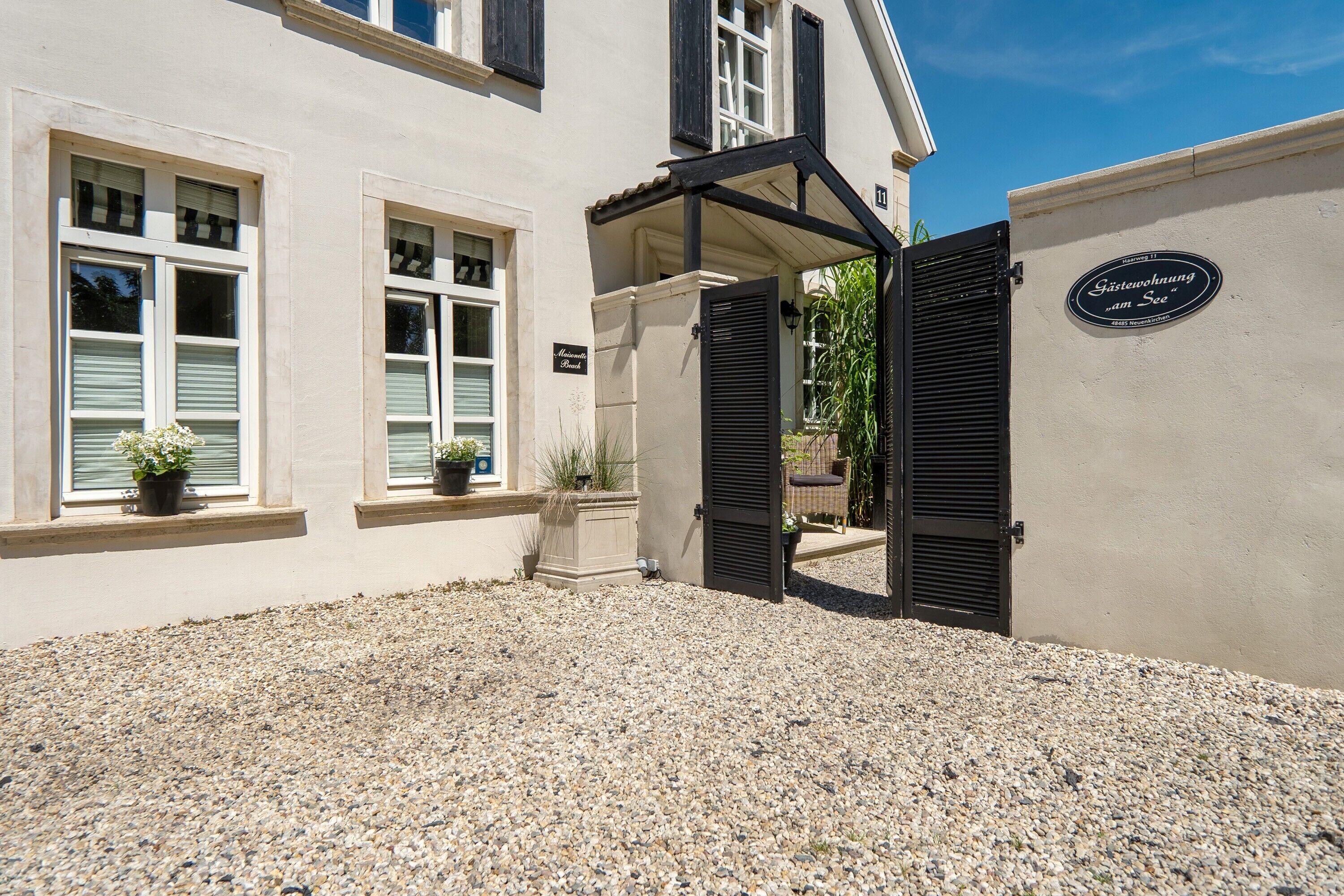 A building with a gravel driveway, a covered entrance, and a sign indicating a guesthouse.