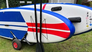 A white and blue inflatable raft with red stripes, a black handle, and a wheel, set on grass. - Cottage and Garden Lakefront Holiday Home with Sauna (Wettringen)