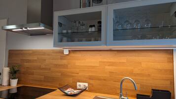 Een moderne keuken met een houten spatwand, een ingebouwde oven, een gootsteen met een kraan en een glazen kast boven het aanrecht.