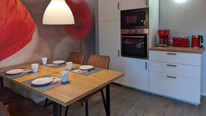 A modern kitchen with white cabinets, a microwave, oven, and red coffee maker.