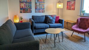 A living room with a sofa, a chair, a small table, and wall art. - Holiday Apartment "Goldgrube Attic" with Wi-Fi (Koblenz)
