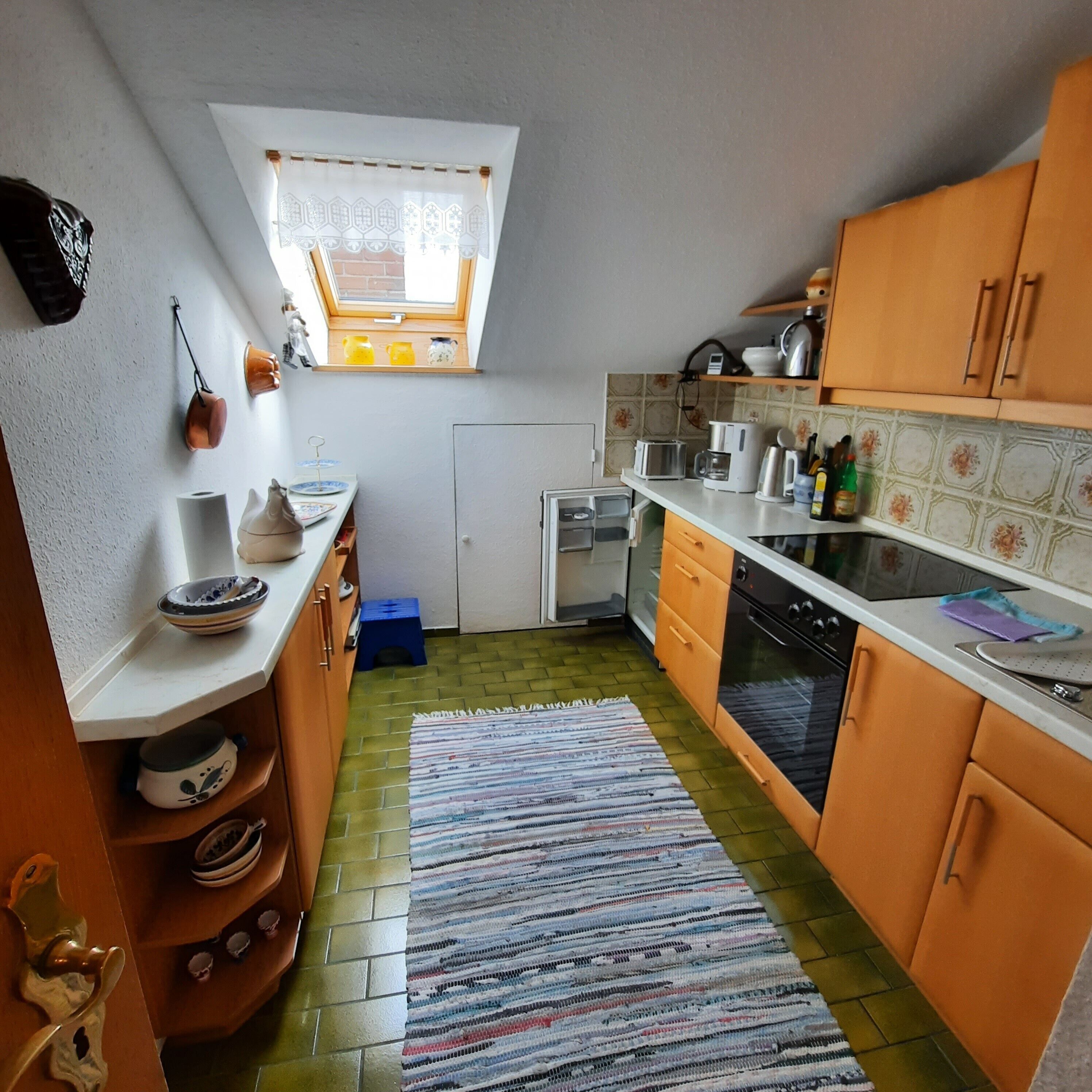 A compact kitchen with a window, a dishwasher, and a stove.