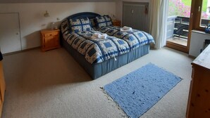 A bedroom with a bed, a nightstand, a radiator, and a view of the outdoors.