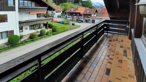 A balcony with a view of a residential area, including houses and a mountain in the background.