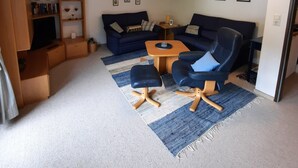 A loft-style living room with a sofa, chairs, a coffee table, and a bookshelf.