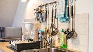 Una cocina con un lavamanos de acero inoxidable, una cafetera y diversos utensilios colgando en la pared.