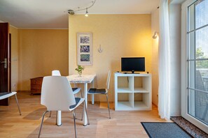 Una sala moderna con una mesa de comedor, sillas, un televisor sobre un mueble bajo y un ventanal grande.