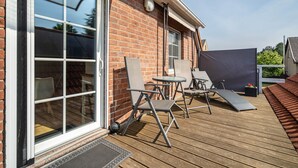 A patio with a table and chairs, a sliding glass door, and a brick wall. - Apartment 'Ferienwohnung 2 Schulze' with Private Terrace, Shared Garden and Wi-Fi (Neustrelitz)