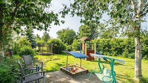 A garden with a play area, including a swing set and a playhouse. - Apartment 'Ferienwohnung 2 Schulze' with Private Terrace, Shared Garden and Wi-Fi (Neustrelitz)