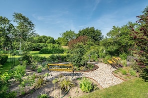 Un jardín con un sendero sinuoso, un banco y diversas plantas.