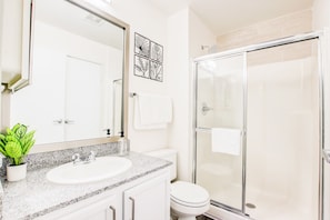 A bathroom with a white sink, a toilet, and a glass-enclosed shower.