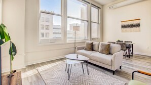 Una sala de estar moderna con un sofá, una mesa de centro y un amplio ventanal con vistas a la ciudad.